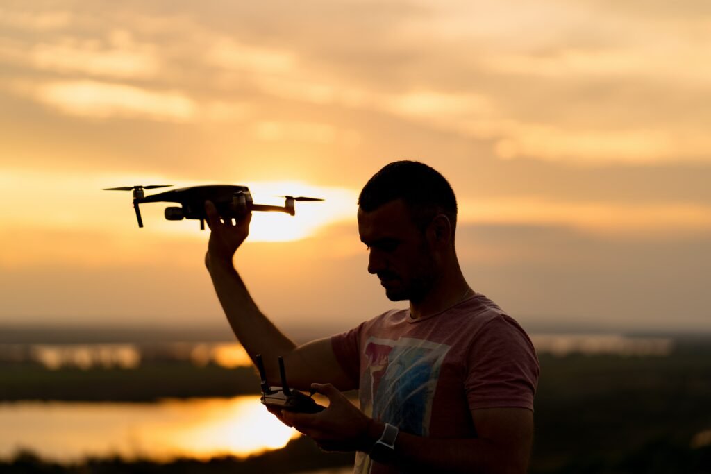 5 innovations qui transforment l’agriculture africaine Silhouette Man Piloting Drone Sunset With Sunny Sky Background Min 1024x683